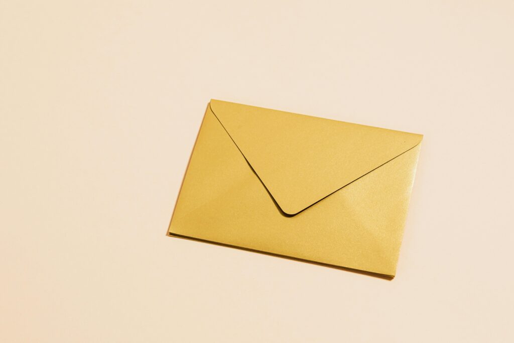 A sleek gold envelope placed on a vibrant yellow background, perfect for postal themes.